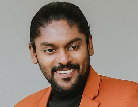 image of singer Vidhu Prathap in Orange coat